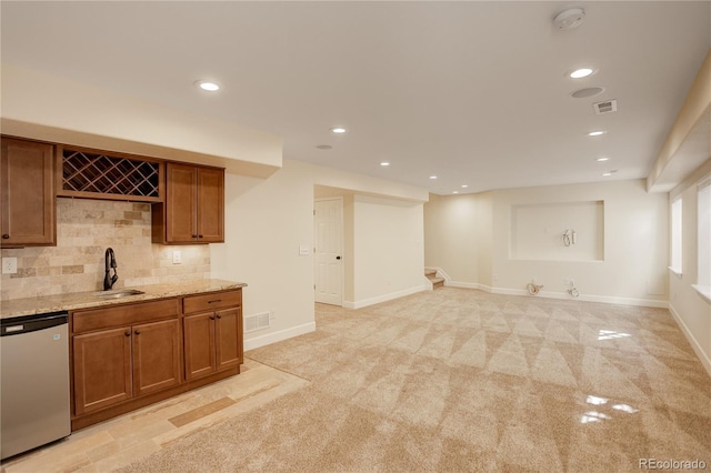 kitchen featuring light stone counters, brown cabinetry, visible vents, decorative backsplash, and stainless steel dishwasher