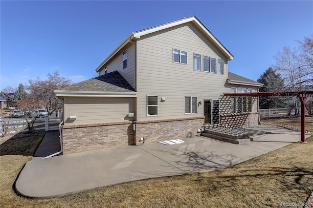 back of property featuring brick siding, roof with shingles, and a patio area