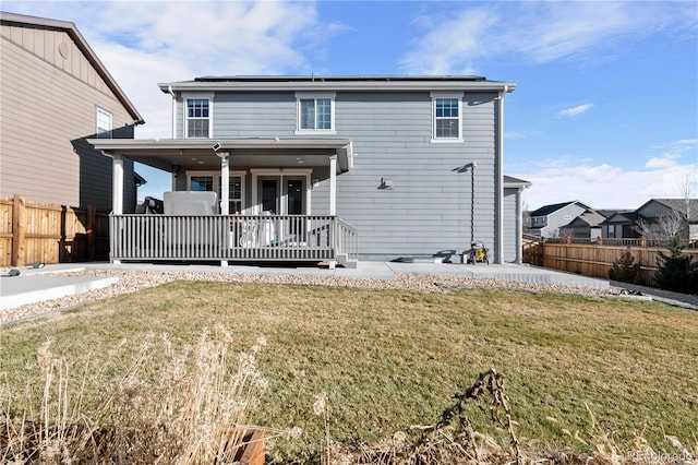 back of property featuring a lawn and a deck