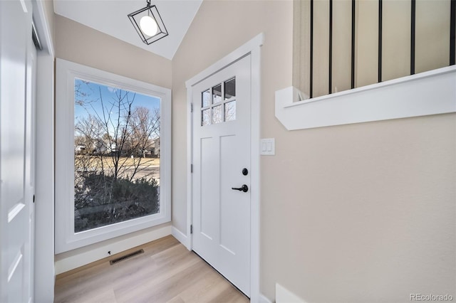 doorway featuring lofted ceiling and light hardwood / wood-style floors