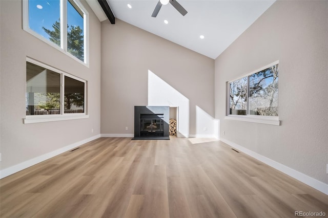 unfurnished living room featuring beamed ceiling, ceiling fan, high vaulted ceiling, and light hardwood / wood-style flooring