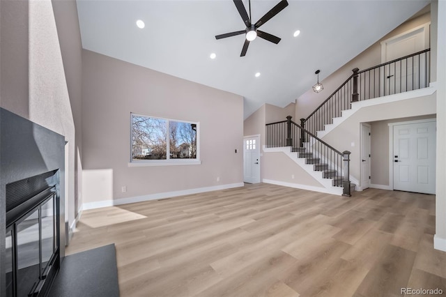 unfurnished living room with ceiling fan, high vaulted ceiling, and light hardwood / wood-style floors