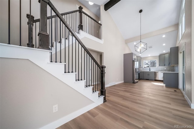 stairs with hardwood / wood-style flooring, sink, high vaulted ceiling, and beamed ceiling