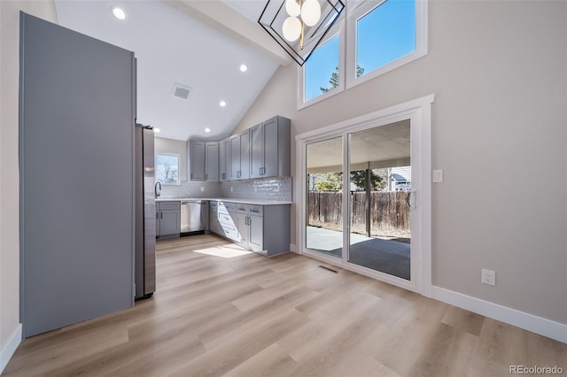 kitchen with gray cabinetry, light wood-type flooring, a healthy amount of sunlight, and appliances with stainless steel finishes