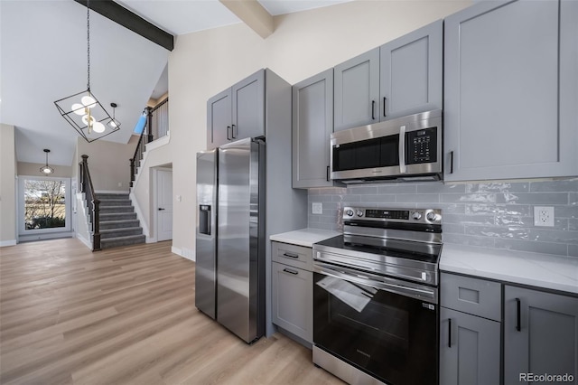 kitchen with pendant lighting, appliances with stainless steel finishes, and gray cabinets