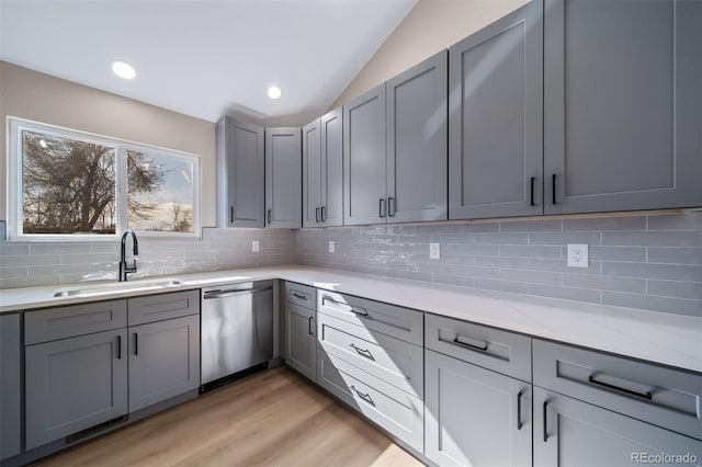 kitchen featuring sink, gray cabinetry, backsplash, light stone countertops, and stainless steel dishwasher