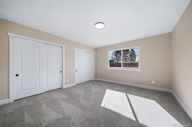 unfurnished bedroom with two closets and carpet