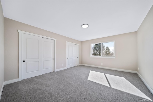 unfurnished bedroom with carpet floors and two closets