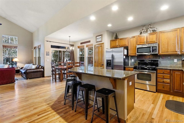 kitchen featuring stainless steel appliances, backsplash, light wood-style flooring, a kitchen island, and a kitchen breakfast bar