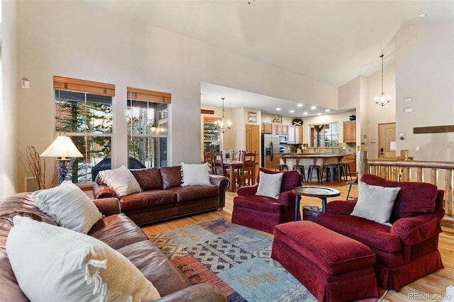 living room featuring an inviting chandelier, high vaulted ceiling, and light wood-style floors