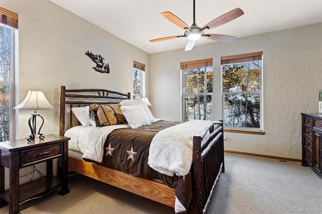 bedroom featuring carpet floors, a textured wall, baseboards, and a ceiling fan