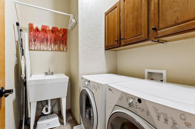 laundry room with washer and dryer, cabinet space, and a textured wall