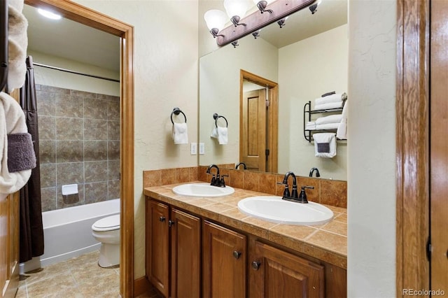 bathroom featuring tile patterned flooring, a sink, toilet, and double vanity