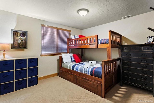 bedroom with a textured ceiling, carpet, visible vents, and baseboards