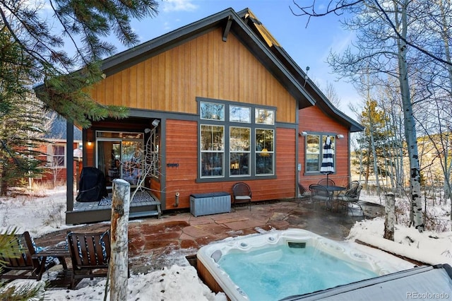 snow covered property featuring an outdoor hot tub and a patio