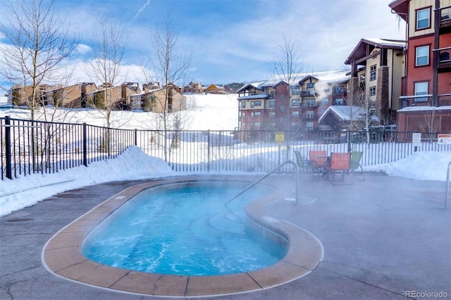 snow covered pool with a fenced backyard and a residential view