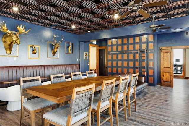 dining room with an ornate ceiling, ceiling fan, wood finished floors, and a barn door