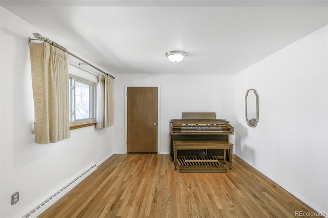 living area with baseboards, baseboard heating, and wood finished floors