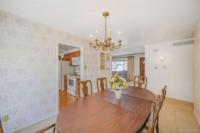 dining space with wallpapered walls, visible vents, and a notable chandelier