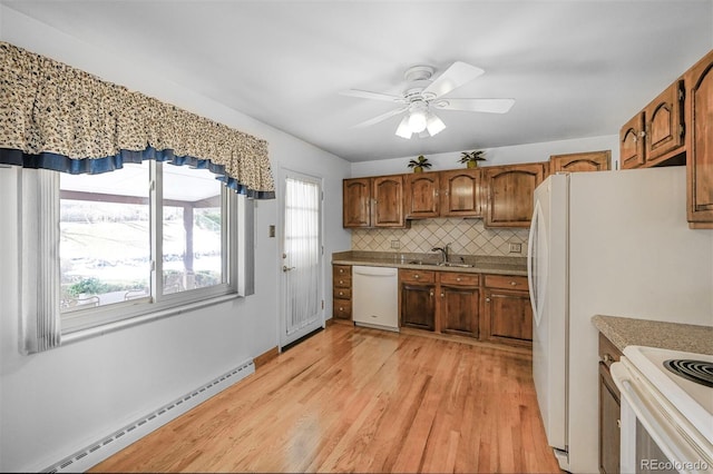 kitchen with a baseboard radiator, white appliances, a sink, light wood-type flooring, and backsplash