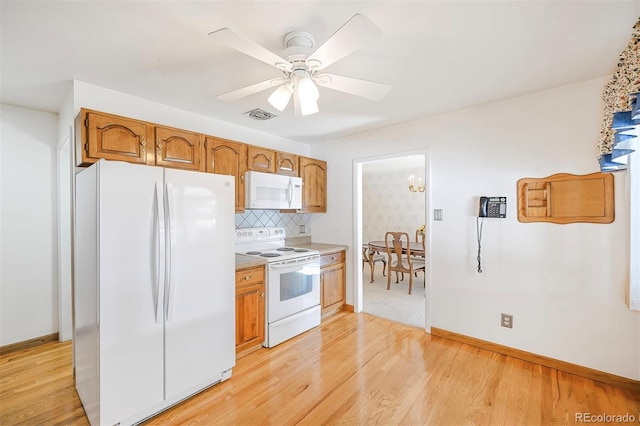 kitchen with white appliances, visible vents, backsplash, and light wood finished floors