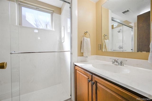 full bath featuring a stall shower, vanity, and visible vents