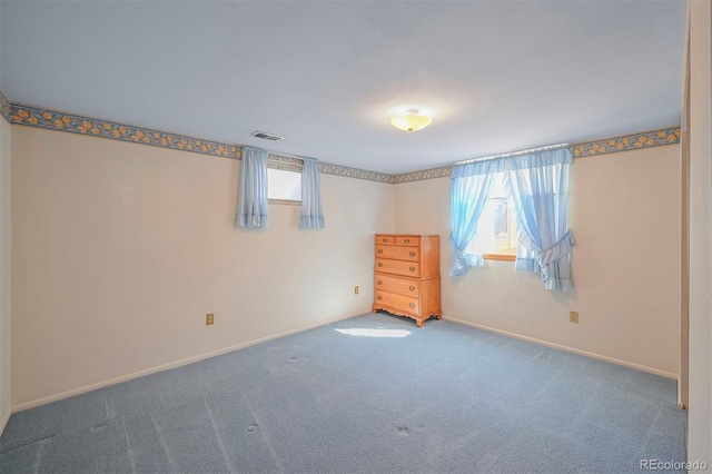 carpeted spare room with a wealth of natural light, visible vents, and baseboards