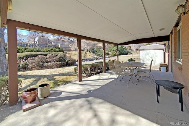 view of patio featuring a storage shed, outdoor dining area, and an outbuilding