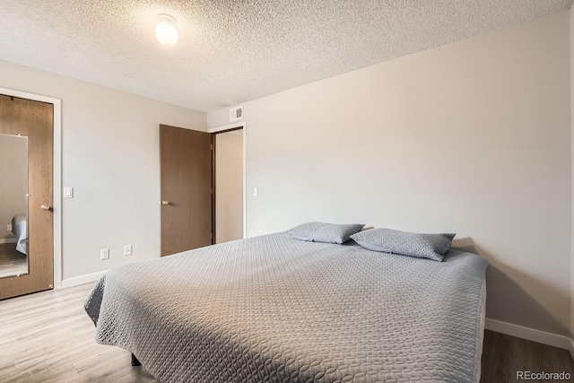 bedroom with wood-type flooring and a textured ceiling