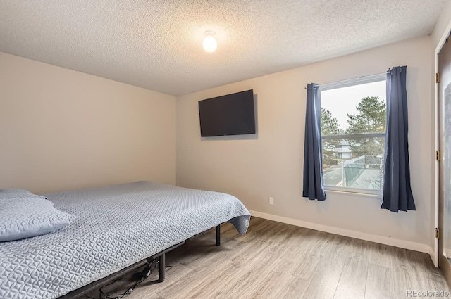 bedroom featuring a textured ceiling and light hardwood / wood-style flooring