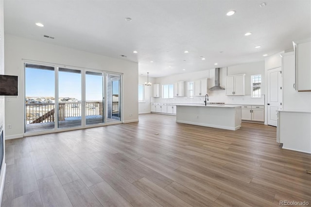 unfurnished living room with sink, light hardwood / wood-style flooring, and a notable chandelier