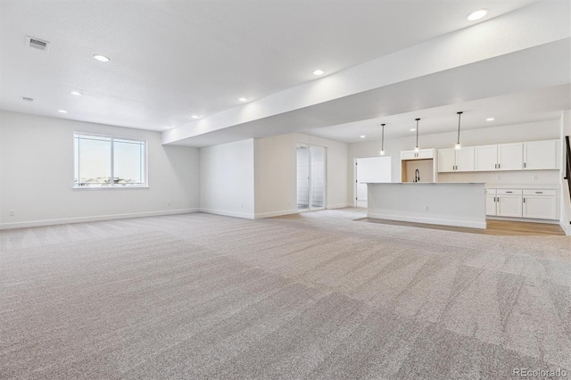 unfurnished living room featuring sink and light colored carpet