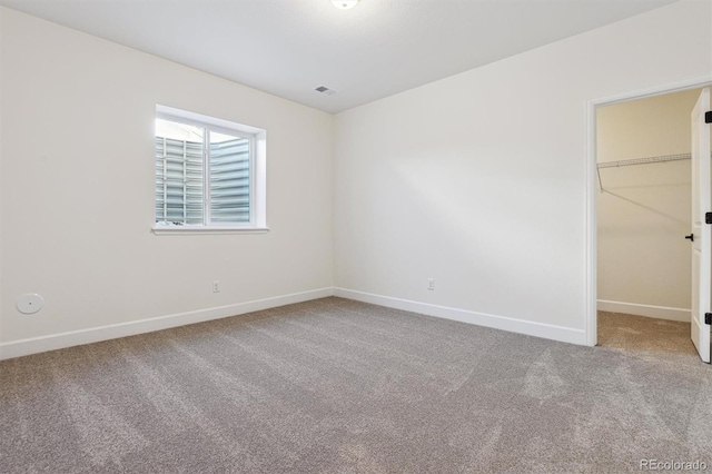 unfurnished bedroom with a walk in closet, a closet, and carpet