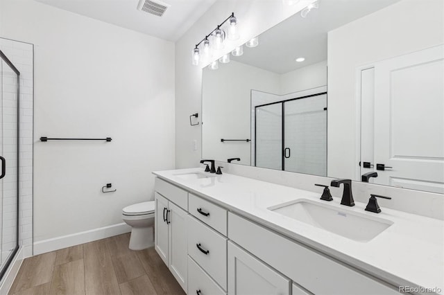 bathroom featuring wood-type flooring, toilet, a shower with shower door, and vanity