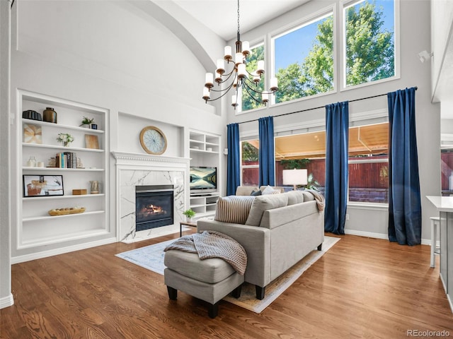 9464 E Aspen Hill Pl, Lone Tree, CO 80124 - living room featuring a chandelier, built in features, wood finished floors, a premium fireplace, and healthy amount of natural light