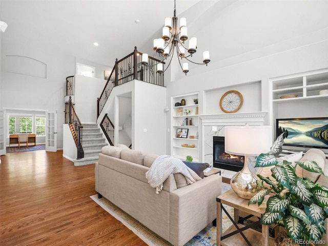 9464 E Aspen Hill Pl, Lone Tree, CO 80124 - living room featuring built in shelves, a towering ceiling, wood finished floors, stairway, and a high end fireplace