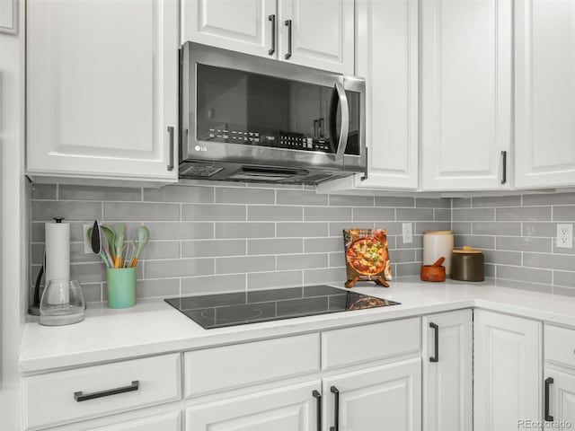 9464 E Aspen Hill Pl, Lone Tree, CO 80124 - kitchen with stainless steel microwave, black electric cooktop, white cabinetry, and tasteful backsplash