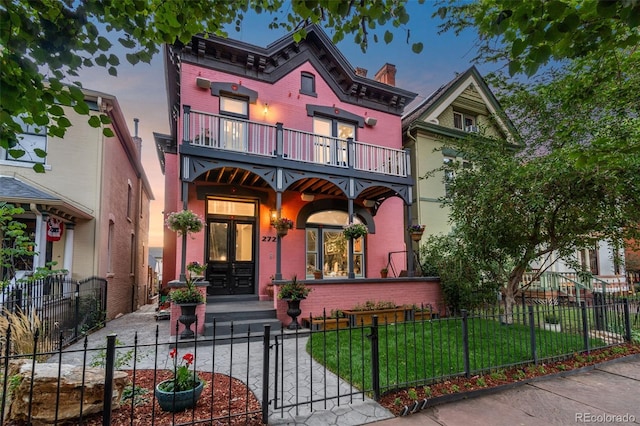 view of front of house with a fenced front yard, brick siding, a gate, a balcony, and a front lawn