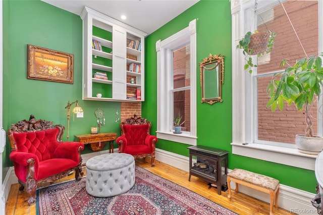 living area featuring baseboards, a wood stove, and wood-type flooring