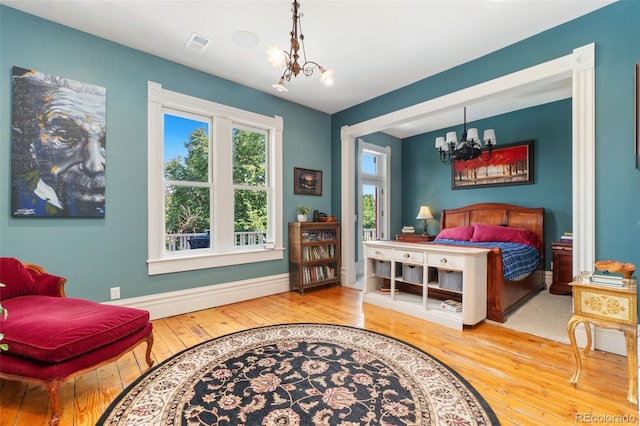 bedroom featuring an inviting chandelier, hardwood / wood-style floors, baseboards, and visible vents