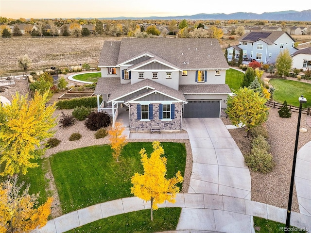 view of front facade with a garage, driveway, stone siding, fence, and a front lawn