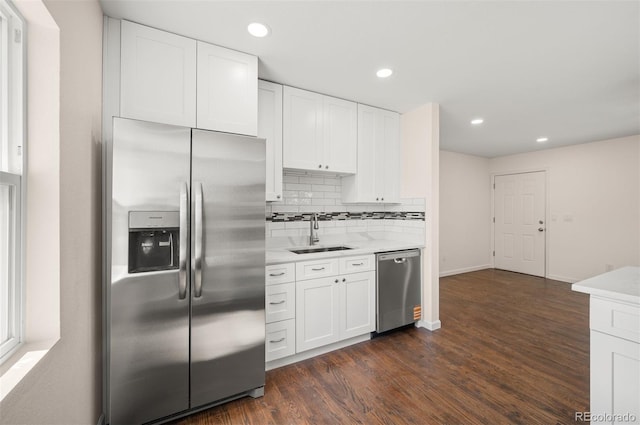 7870 Magnolia St, Commerce City, CO 80022 - kitchen with stainless steel appliances, a sink, dark wood finished floors, white cabinetry, and decorative backsplash