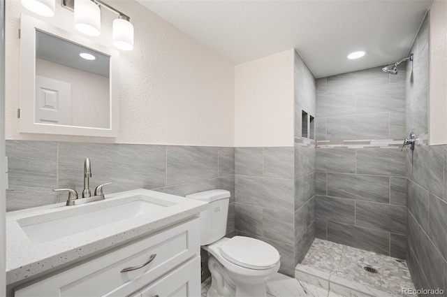 7870 Magnolia St, Commerce City, CO 80022 - bathroom featuring tiled shower, toilet, vanity, tile walls, and marble finish floors