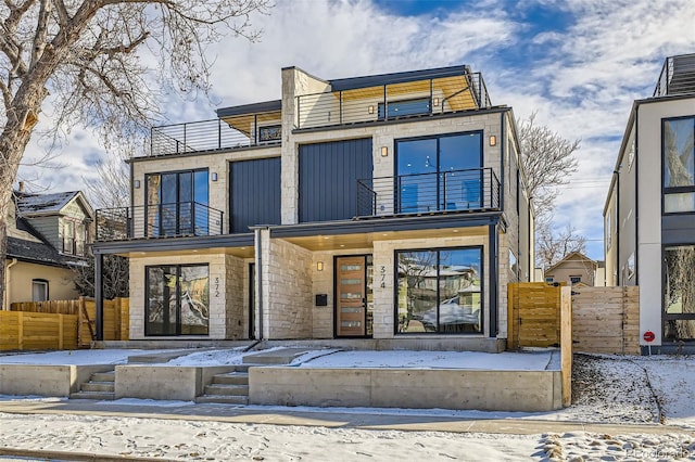 contemporary house featuring a balcony and fence