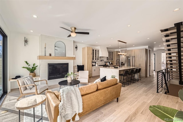 living room featuring recessed lighting, ceiling fan, light wood finished floors, and a fireplace