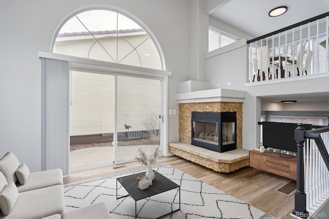 living room featuring light wood-type flooring and a towering ceiling