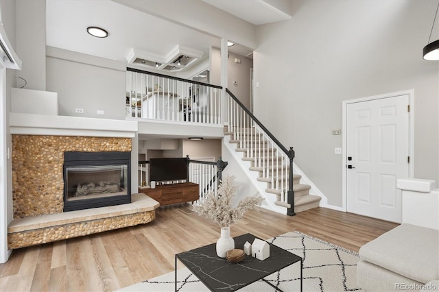 living room featuring a high ceiling, hardwood / wood-style flooring, and a tiled fireplace