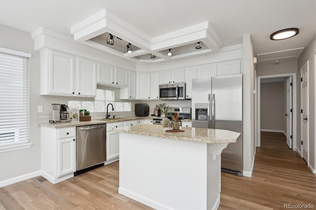 kitchen with light stone counters, a center island, stainless steel appliances, white cabinetry, and coffered ceiling