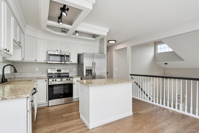 kitchen featuring stainless steel appliances, sink, white cabinetry, beamed ceiling, and a kitchen island