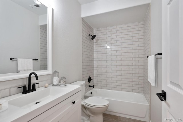 full bathroom featuring toilet, vanity, and tiled shower / bath